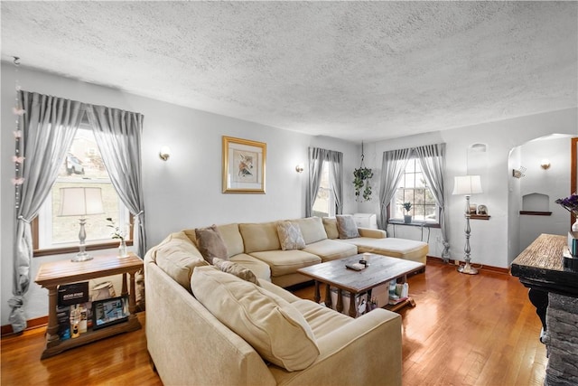 living room with baseboards, arched walkways, hardwood / wood-style floors, and a textured ceiling