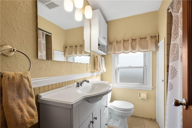 bathroom with a textured wall, a wealth of natural light, visible vents, and toilet