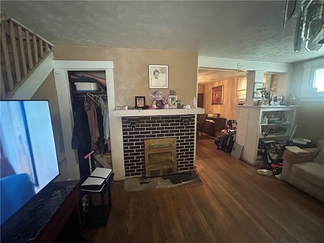 living room featuring a fireplace with flush hearth, a textured ceiling, and wood finished floors