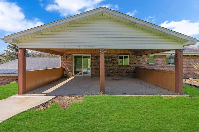 exterior space featuring a carport, a yard, a patio, and brick siding