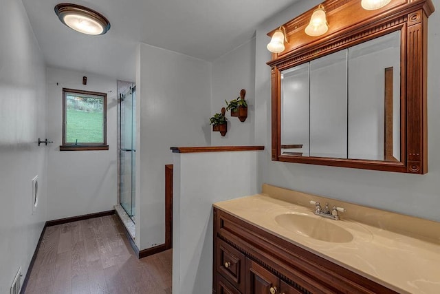 bathroom with vanity, baseboards, a shower stall, visible vents, and wood finished floors