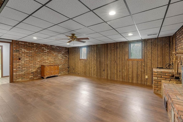 below grade area with a paneled ceiling, wood finished floors, visible vents, and plenty of natural light