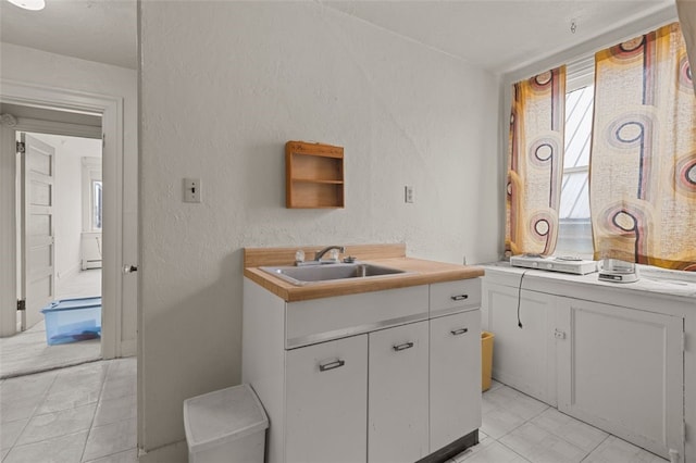 826 Collins Ave, Highland Park, PA 15206 - kitchen featuring light countertops, a textured wall, a sink, and white cabinetry
