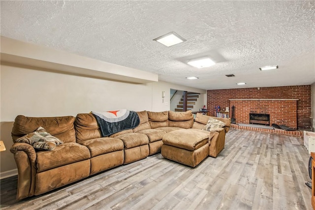 living room featuring a brick fireplace, wood finished floors, a textured ceiling, and stairs