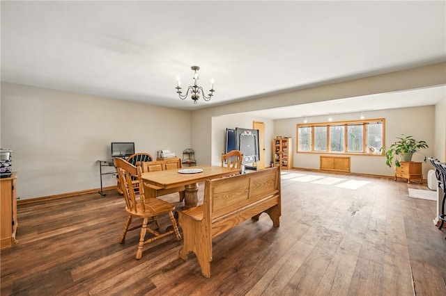 dining space with baseboards, a chandelier, and wood finished floors