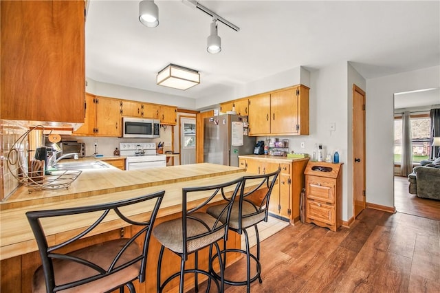 kitchen featuring light countertops, a sink, light wood-type flooring, a peninsula, and appliances with stainless steel finishes