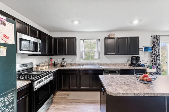 106 Morgan Dr, South Strabane, PA 15301 - kitchen featuring light wood finished floors, stainless steel appliances, light countertops, dark cabinetry, and a sink