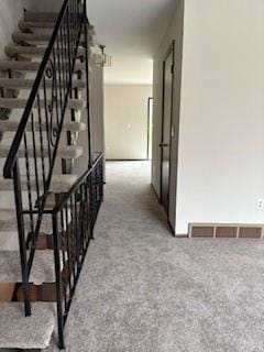 hallway featuring stairway, visible vents, and carpet flooring