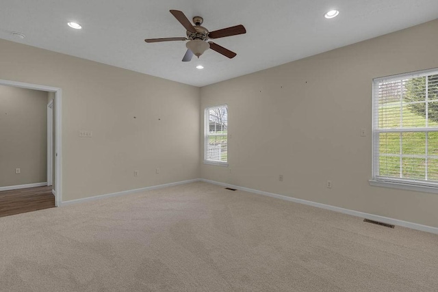 spare room featuring light colored carpet, ceiling fan, plenty of natural light, baseboards, and recessed lighting