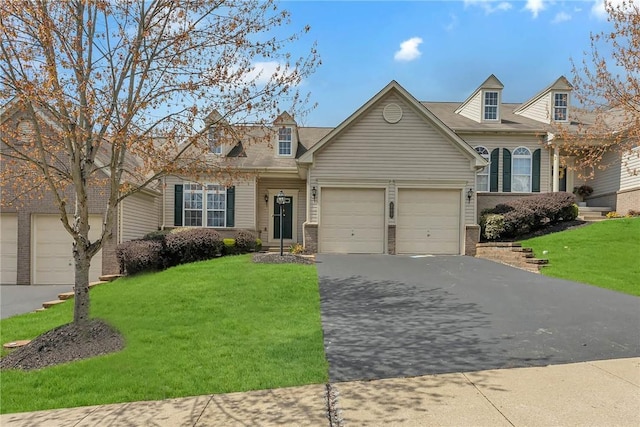 new england style home with driveway, a front yard, a garage, and brick siding