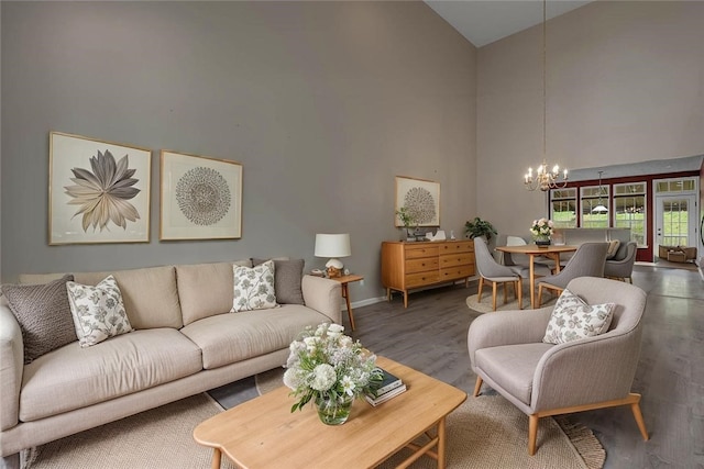 living room featuring high vaulted ceiling, a chandelier, wood finished floors, and baseboards