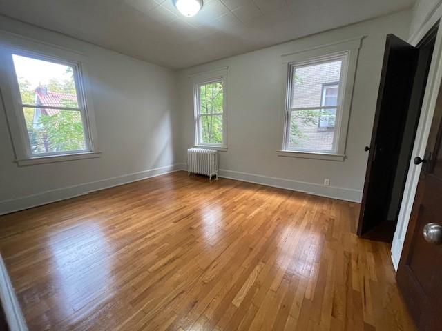 6605 Woodwell St, Squirrel Hill, PA 15217 - empty room with radiator heating unit, baseboards, and light wood-type flooring
