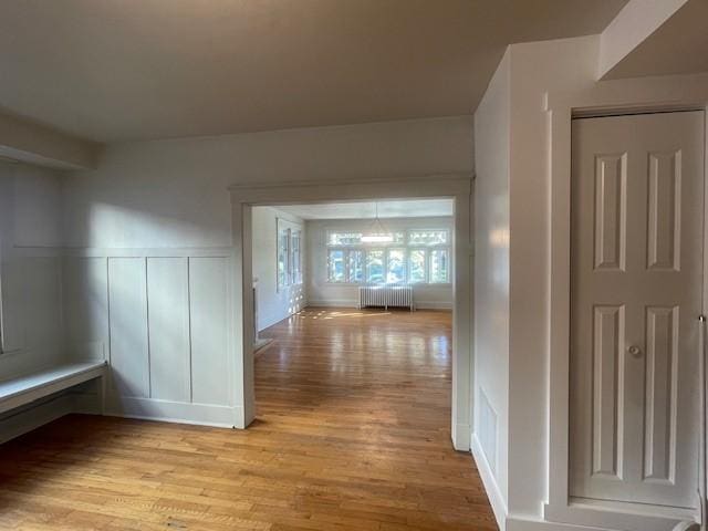 6605 Woodwell St, Squirrel Hill, PA 15217 - hallway with a decorative wall, radiator heating unit, a wainscoted wall, and light wood-type flooring