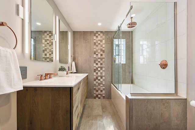 full bath featuring wood finished floors, a sink, walk in shower, double vanity, and recessed lighting