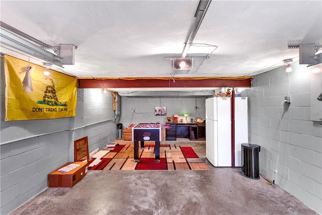 garage with a garage door opener, concrete block wall, and freestanding refrigerator
