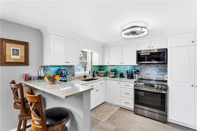 kitchen featuring a breakfast bar, backsplash, appliances with stainless steel finishes, and a sink