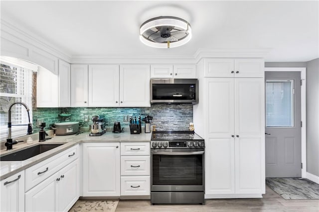 kitchen with white cabinets, a sink, appliances with stainless steel finishes, and tasteful backsplash