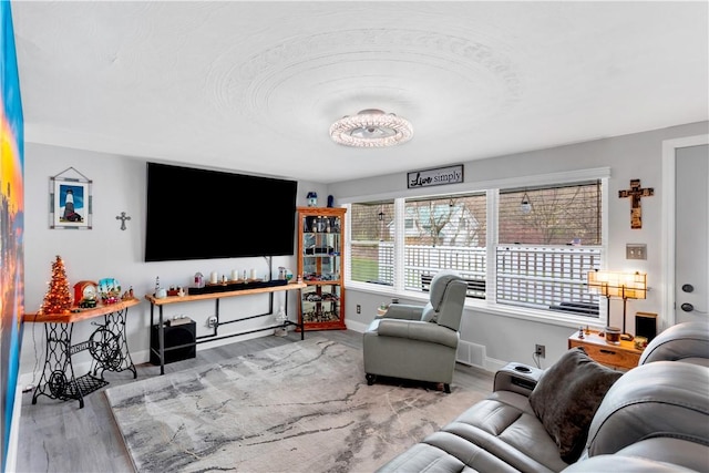 living area with wood finished floors, visible vents, and baseboards