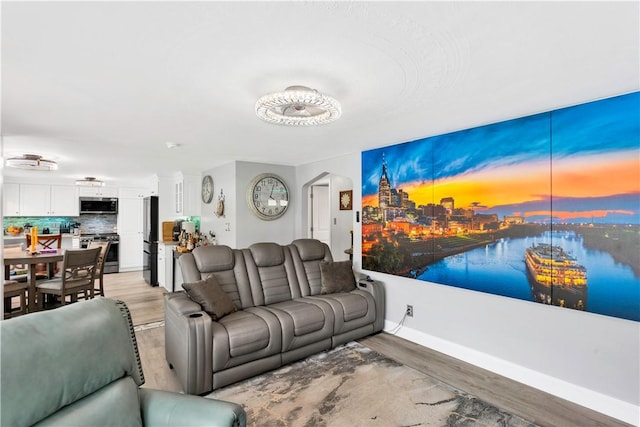 living room featuring light wood-type flooring, baseboards, arched walkways, and a water view