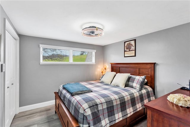 bedroom with baseboards, wood finished floors, and a closet
