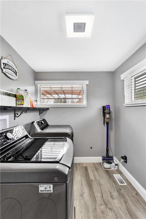 clothes washing area featuring baseboards, wood finished floors, separate washer and dryer, and laundry area