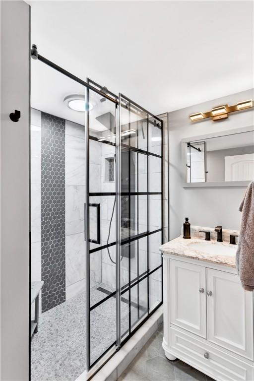 full bathroom with a tile shower and vanity