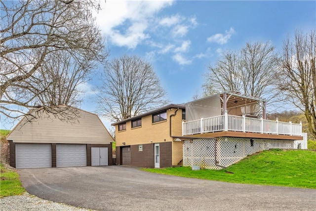 exterior space with a detached garage, a front lawn, an outbuilding, a wooden deck, and brick siding