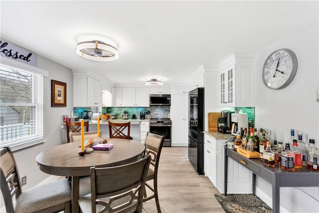kitchen with appliances with stainless steel finishes, tasteful backsplash, white cabinetry, and glass insert cabinets