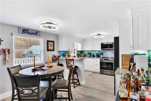 kitchen featuring decorative backsplash, stainless steel appliances, white cabinets, and light countertops