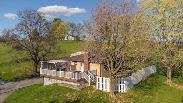 back of house with a wooden deck, a lawn, and fence