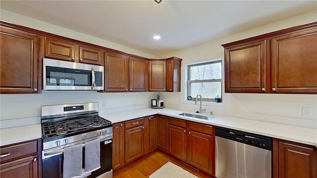 kitchen featuring a sink, light wood finished floors, light countertops, stainless steel appliances, and recessed lighting