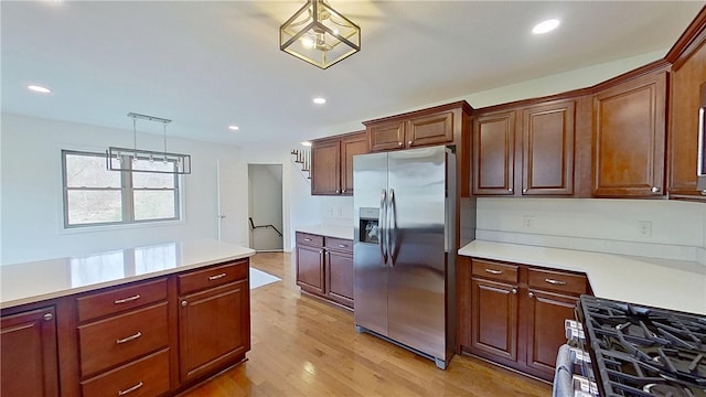 kitchen featuring light countertops, appliances with stainless steel finishes, pendant lighting, and light wood finished floors