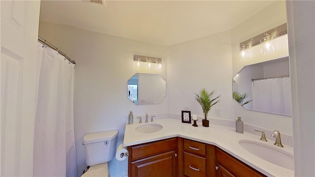 bathroom featuring double vanity, a sink, and toilet