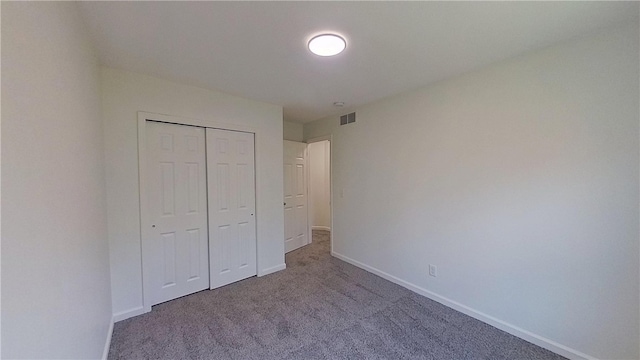 unfurnished bedroom with a closet, baseboards, carpet flooring, and visible vents