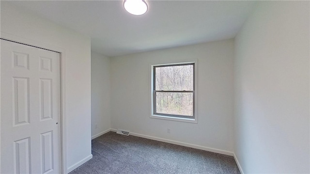 empty room with baseboards, dark carpet, and visible vents