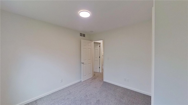 spare room with carpet flooring, baseboards, and visible vents