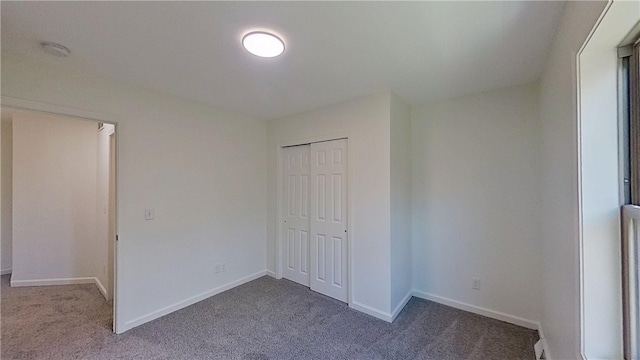 unfurnished bedroom with baseboards, carpet, and a closet