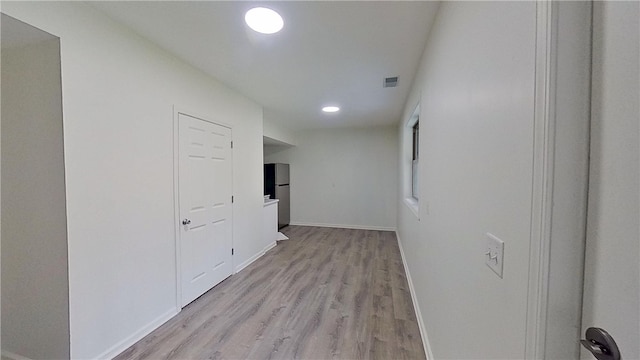hall featuring light wood-type flooring, recessed lighting, baseboards, and visible vents