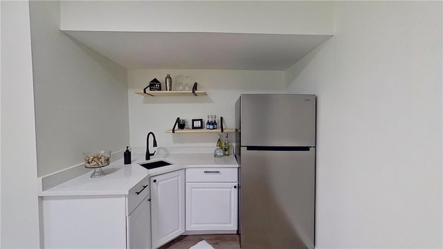 kitchen with open shelves, a sink, light countertops, freestanding refrigerator, and white cabinetry