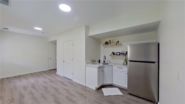 kitchen featuring freestanding refrigerator, open shelves, visible vents, and a sink