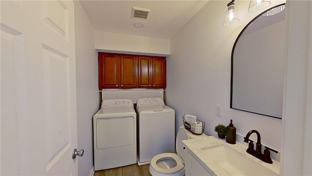 bathroom with washer and dryer, vanity, toilet, wood finished floors, and visible vents