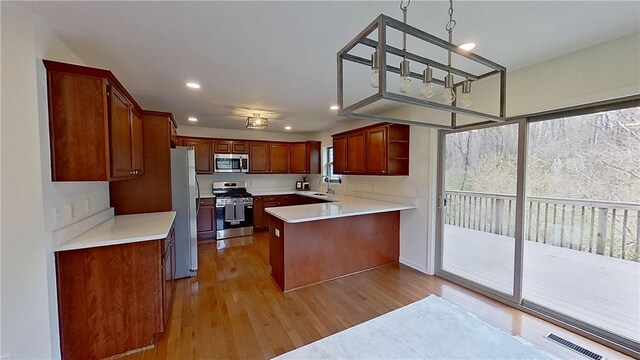 kitchen with appliances with stainless steel finishes, open shelves, light countertops, a peninsula, and light wood-style floors