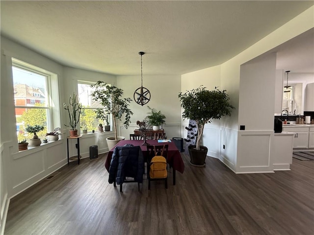 6755 Mcpherson Blvd, Point Breeze, PA 15208 - dining space with a decorative wall, an inviting chandelier, a wainscoted wall, dark wood finished floors, and visible vents