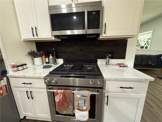 6755 Mcpherson Blvd, Point Breeze, PA 15208 - kitchen featuring tasteful backsplash, white cabinetry, wood finished floors, light stone countertops, and appliances with stainless steel finishes