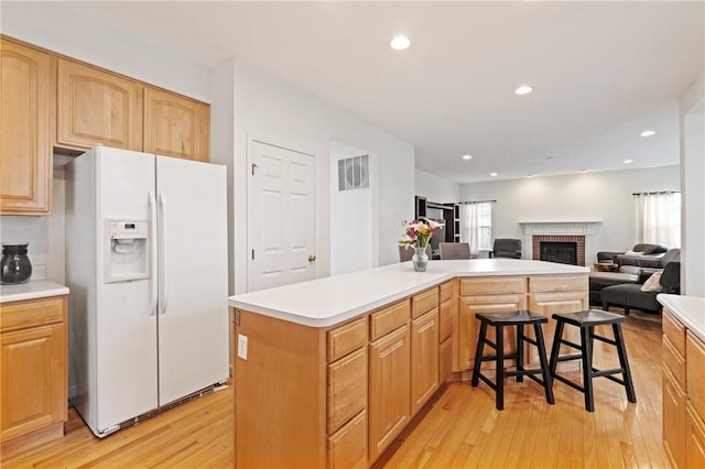 1743 Holmes Dr, Franklin Park, PA 15143 - kitchen with light wood-type flooring, a brick fireplace, a kitchen island, light countertops, and white fridge with ice dispenser