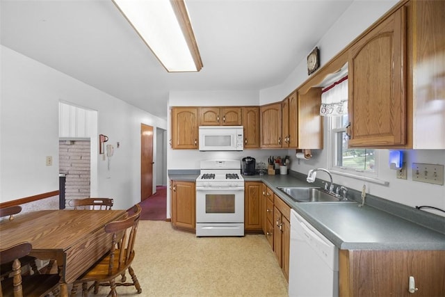 kitchen featuring brown cabinets, dark countertops, a sink, white appliances, and light colored carpet