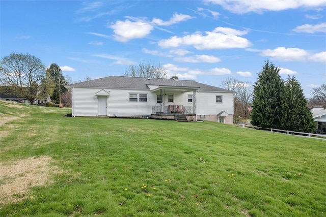 rear view of house with fence and a lawn