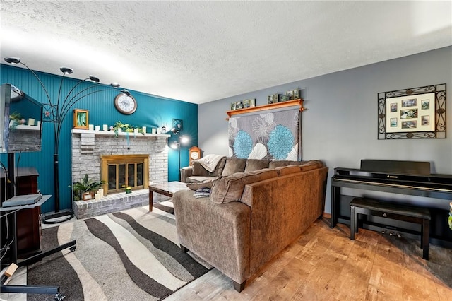 living room with a brick fireplace, wood finished floors, and a textured ceiling