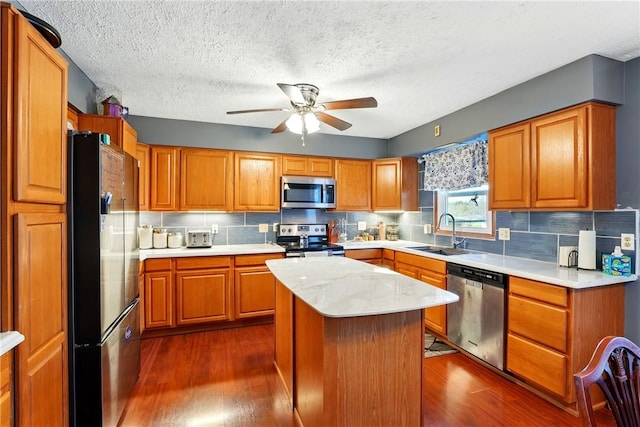 kitchen featuring dark wood-style floors, stainless steel appliances, a sink, decorative backsplash, and ceiling fan
