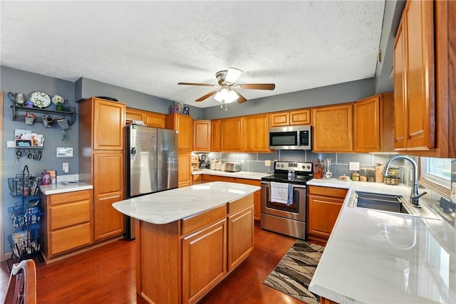 kitchen featuring dark wood-style floors, a sink, a textured ceiling, a ceiling fan, and appliances with stainless steel finishes